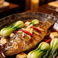 Braised whole sea bass in a serving dish